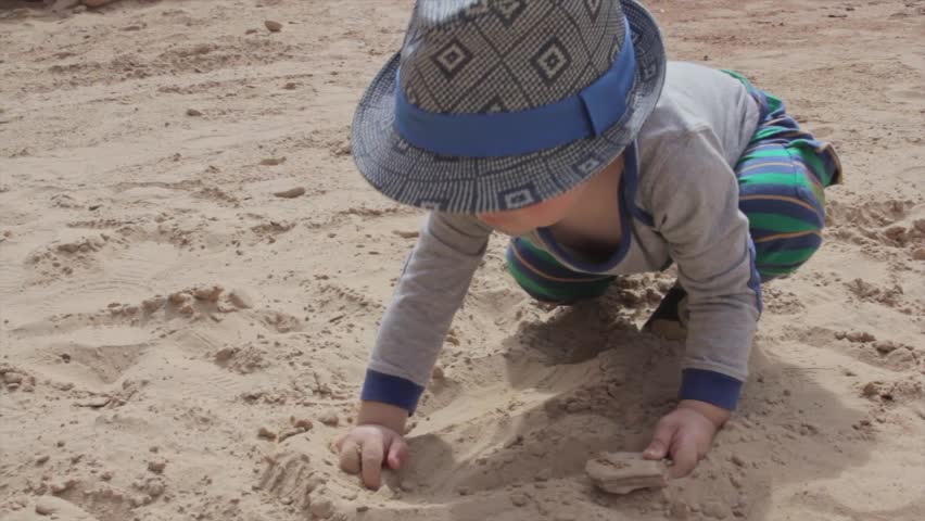 A cute little boy playing in the sand in the desert