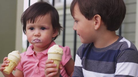 Brother and sister eating ice cream cones together
