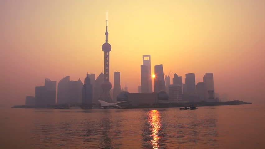 China - January 2012: Warm tone view of sunrise behind modern Shanghai cityscape with Oriental Pearl Tower, Huangpu River, Pudong district in Shanghai, China in January, 2012