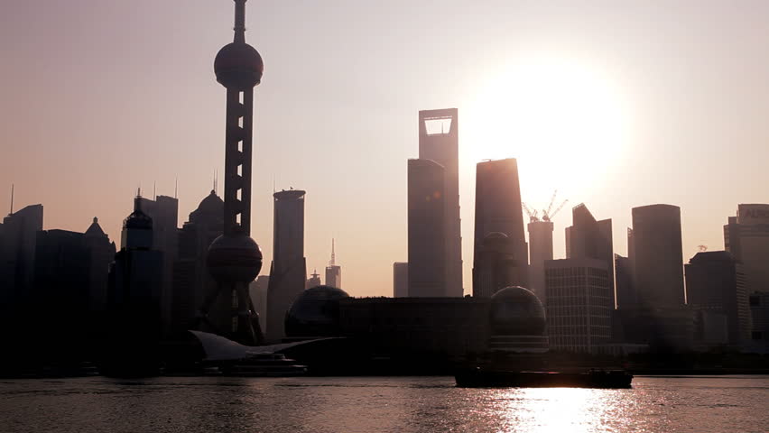 China - January 2012: Water level panorama of sunrise behind a silhouette of the Shanghai skyline with the Oriental Pearl Tower, Huangpu River, Pudong district, Shanghai, China in January, 2012