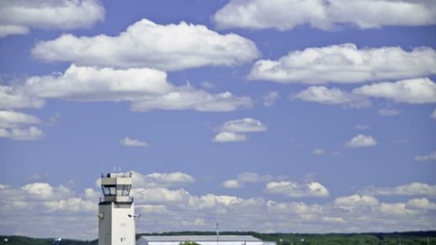 A time-lapse clip of clouds on a blue sky summer day, passing by an airport control tower.