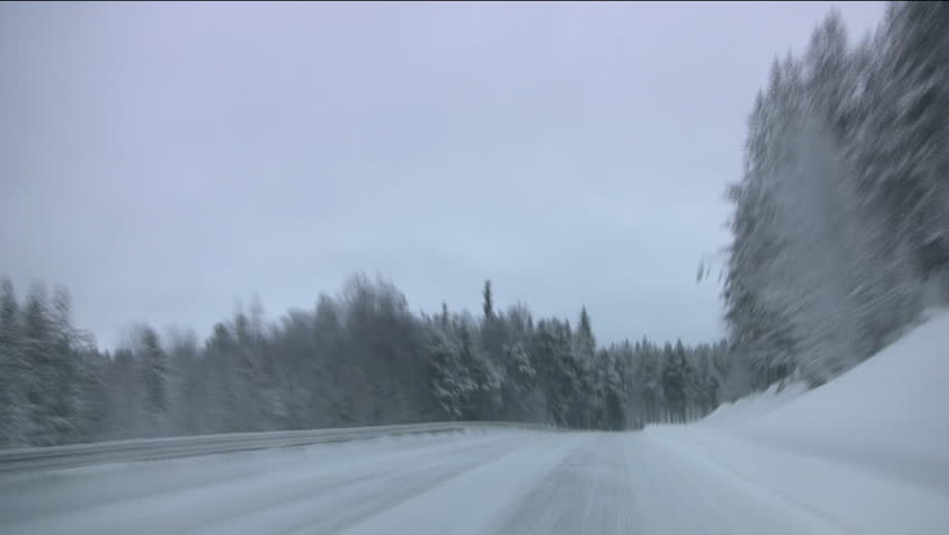 Car quickly goes on winter forest road. Twilight. Finland. Timelapse