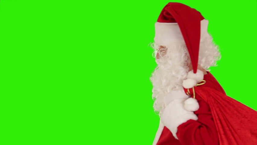 Santa Claus carrying his bag, is looking at camera, sends a kiss and wave, Green