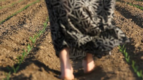 Woman feet step barefoot on spring soil, long skirt in wind breeze