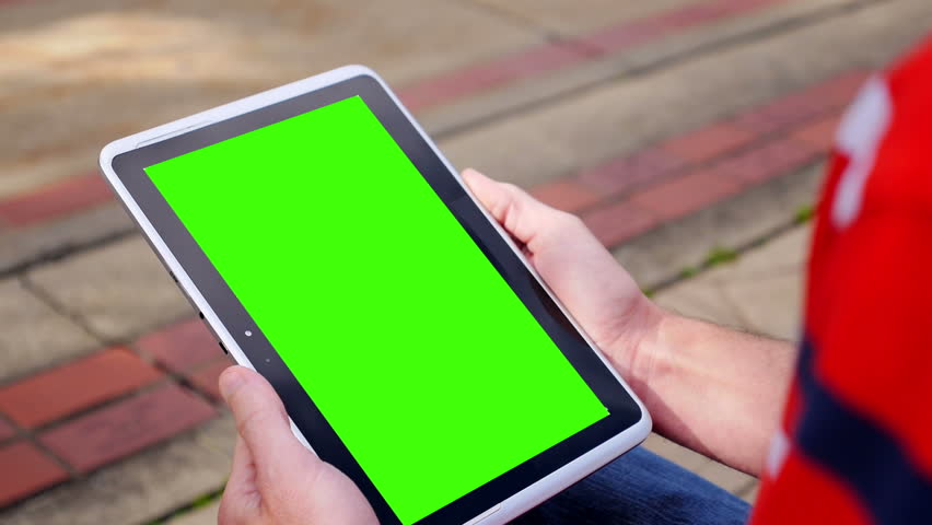 A man holds a blank tablet PC in portrait orientation with a green screen for