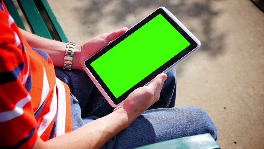 A man on a park bench holds a blank tablet PC in portrait orientation with a
