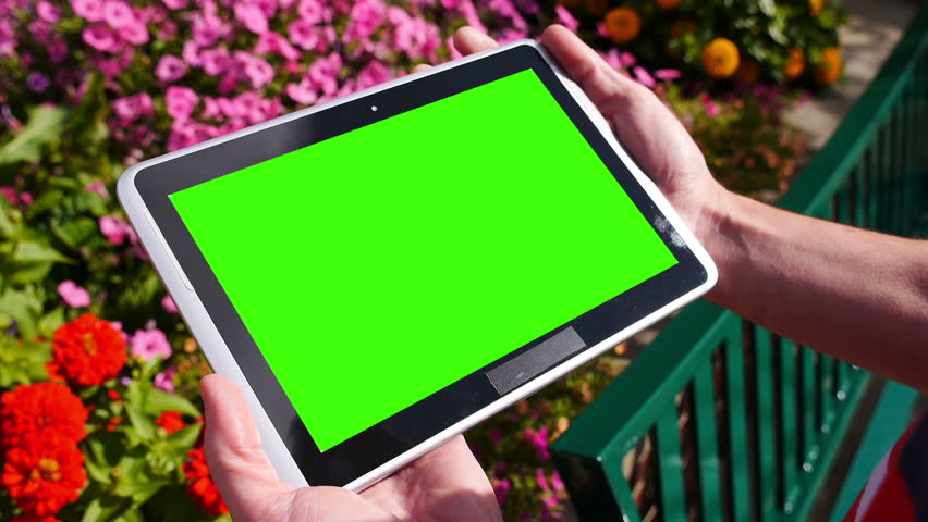 A man holds a blank tablet PC in landscape orientation with a green screen for