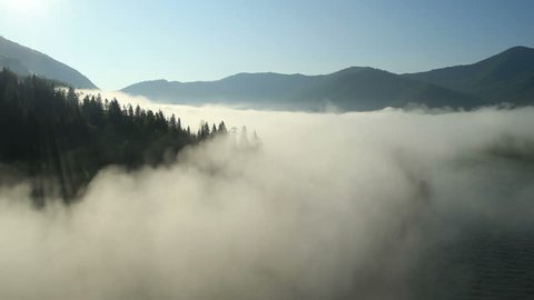 Aerial View. Flying over the high mountains in beautiful clouds . Aerial camera shot.  Air clouds. Altai, Siberia.
