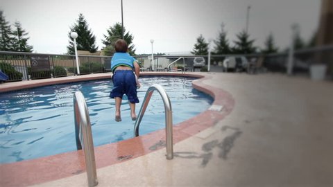 Young boy jumps into swimming pool