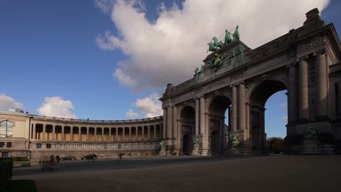 Brussels Triumphal Arch monument at Cinquantenaire park. Photo time-lapse in the afternoon, featuring the arch, one of two colonnades, pedestrians and clouds (Belgium, 2012 Oct).