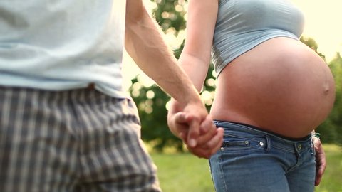 Couple with pregnant woman holding hands and kissing
