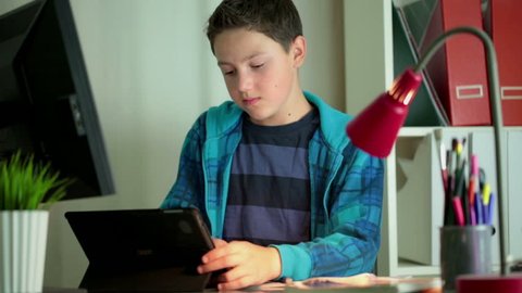 Young boy doing homework with tablet computer in home
