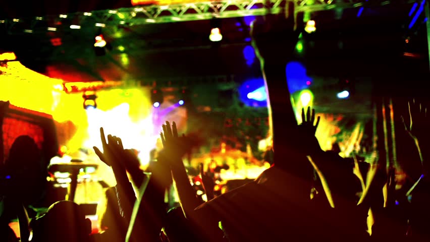 People hands up silhouette backlit and colorful lights on concert. Shot with