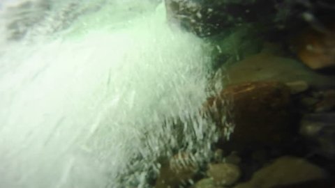 A flurry of bubbles in a cold river. Medium shot.