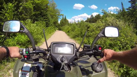 Driving POV on an ATV on a rural wilderness road through a forest