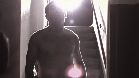 A fighter walks down a hallway towards the camera punching, with a bright light behind him and lens flare