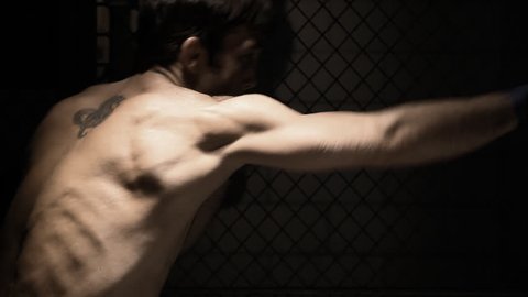 Profile of a mixed martial arts athlete shadow boxing. Medium shot.