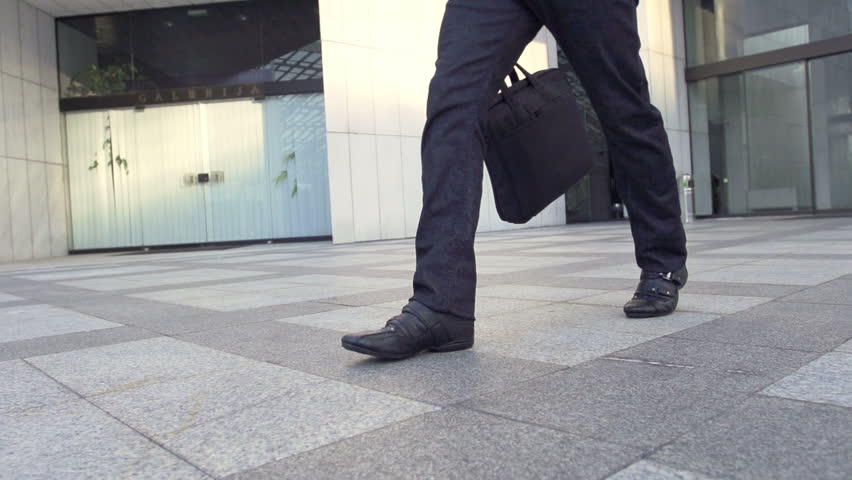 Slow Motion Shot Of A Male Legs Walking Through Business Area. Casually Dressed