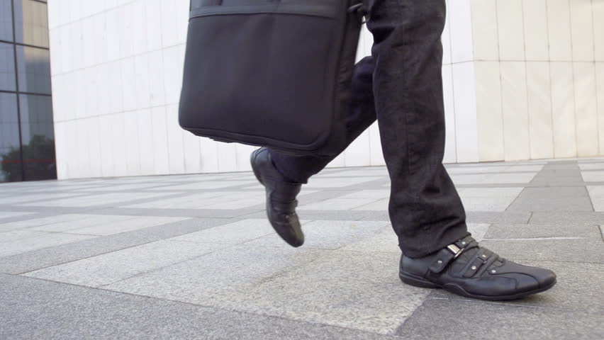 Slow Motion Shot Of A Male Legs Walking. Casually Dressed And Carrying A