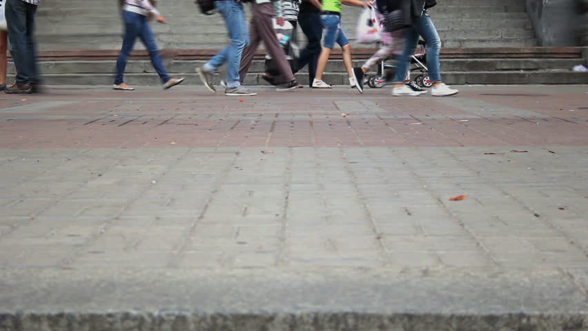Time lapse of different people walking on city pavement tiles