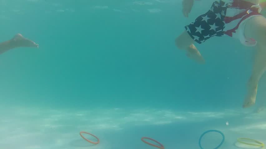 A boy diving for rings at the bottom of a swimming pool underwater shot