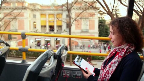 Beautiful young woman listens tour program at tourist bus near museum Prado in Madrid, Spain.