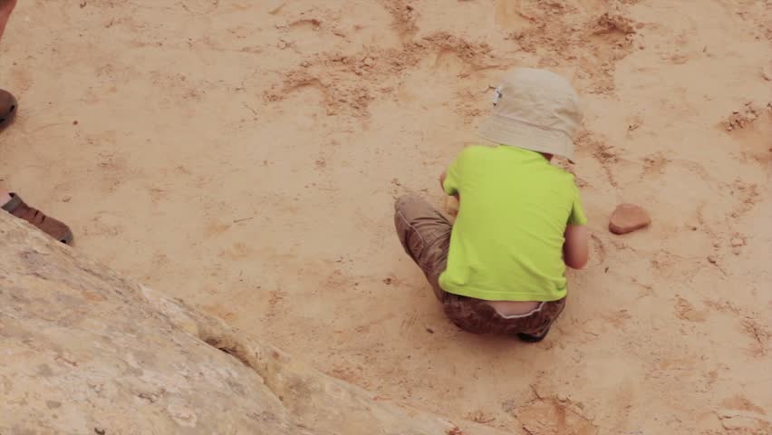 A little boy digging in the desert sand