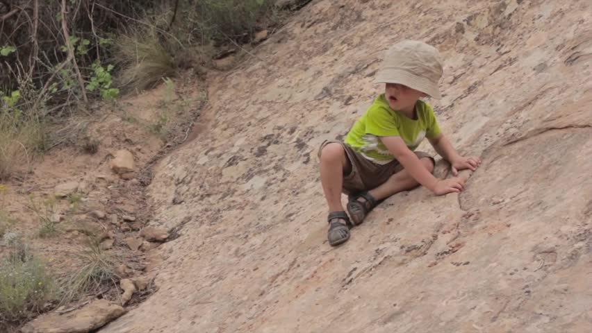 A little boy learning how to climb on rocks in southern utah