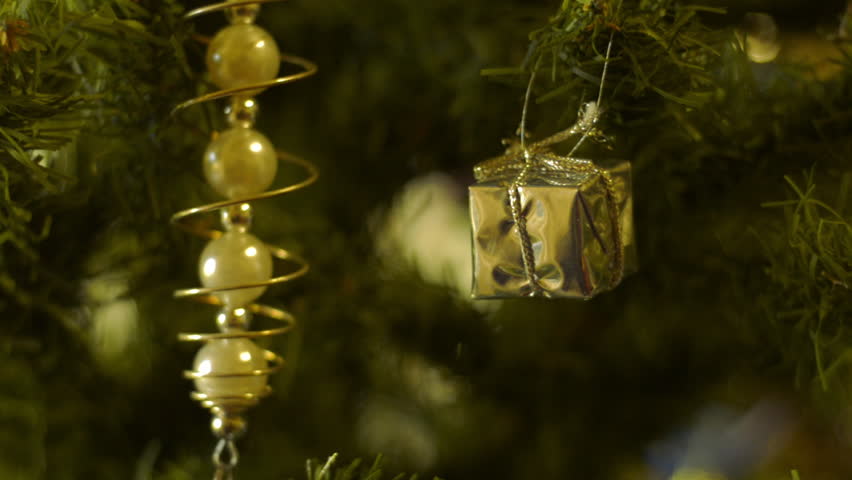 A golden box and other decorations hanging on a Christmas tree