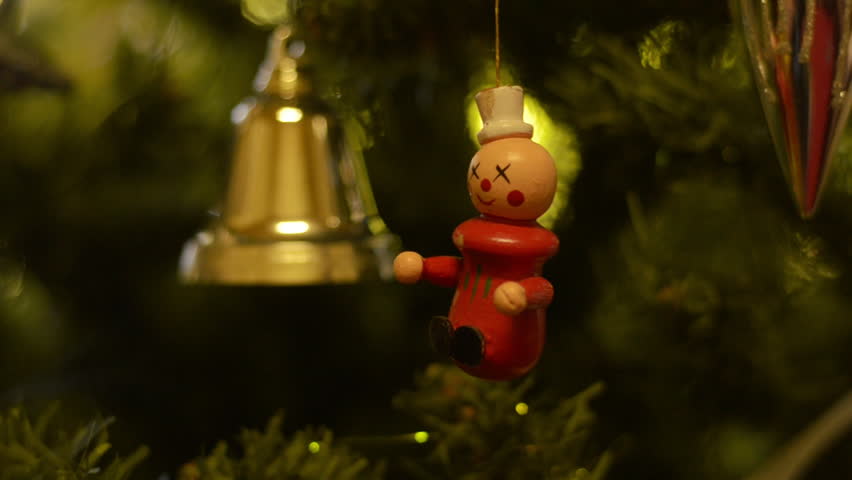 A clown and golden bell hanging on a Christmas tree.