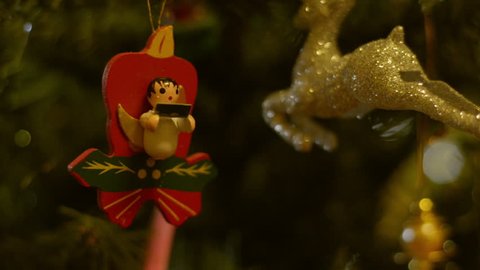 Angel and reindeer decorations hanging on a Christmas tree.
