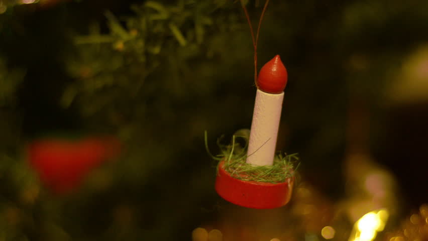 A candle decoration hanging on a Christmas tree.