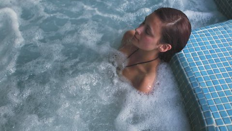 Brunette relaxing in a jacuzzi pool at the hotel spa