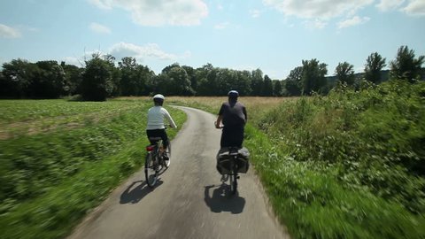 Retired couple cycling on road in countryside