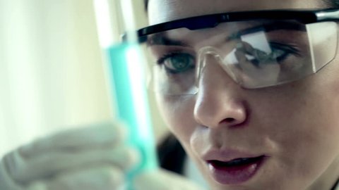 Female scientist examine test tube with blue substance
