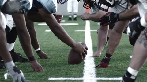 Close up of football players, linemen lining up and snapping the ball and starting the play