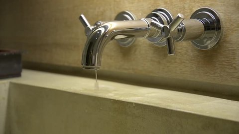 Hand close a dripping water tap faucet in the bathroom