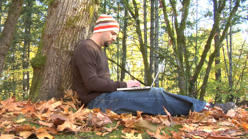 Man sitting in outdoor autumn setting using laptop
