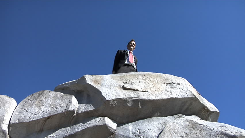 Businessman celebrating on top of rock