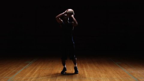 Wide shot of a basketball player catching a pass and then shooting it