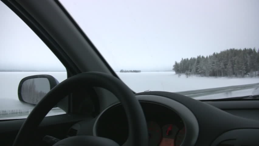 View of the driver's seat of a moving car and the winter forest