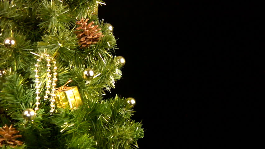 Green Christmas tree (part of) with gold ornaments rotates on a black background