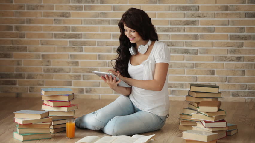 Cute girl in headset sitting on floor using touchpad and smiling at camera