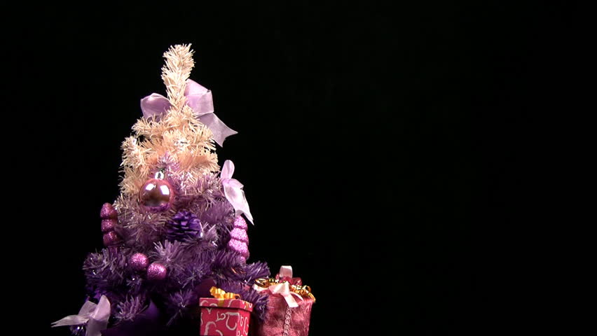 Decorated pink Christmas tree rotates on a black background