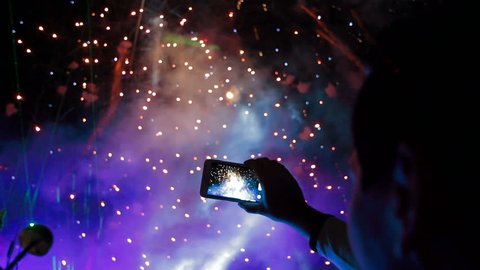 Man filming colorful fireworks on his cell phone.
Filming fireworks.