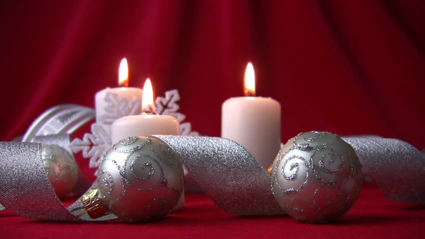 Silver Christmas balls and ribbons. Flame burning white candles trembles breath