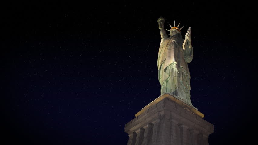 The Statue of Liberty at night.  Stars rotate in the background.