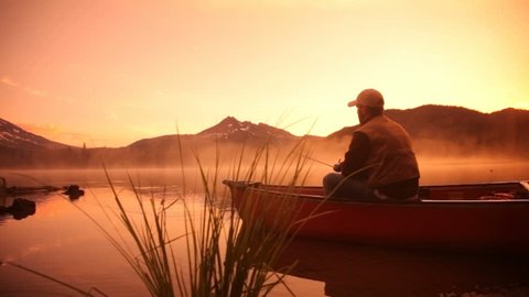 Man fishing in lake at sunrise Stockvideo