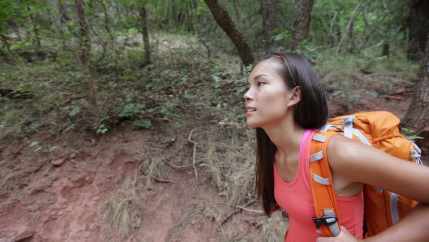 Woman hiking in forest. Female hiker walking with backpack smiling happy in Zion Canyon, Zion National Park, Utah, USA. Multicultural Asian Caucasian active girl living healthy lifestyle outdoors.