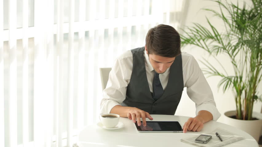 Good-looking man sitting at table and using touchpad